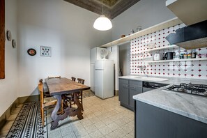 A kitchen with a wooden dining table, white refrigerator, and a tiled backsplash.