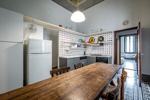 A kitchen with a wooden table, white cabinets, and a patterned backsplash.