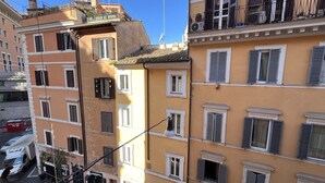 Um edifício de vários andares com varandas, janelas com persianas e vista para a rua.