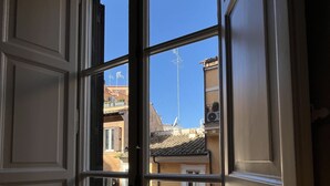 Janela com vista para edifícios próximos e céu claro.
