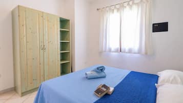Een slaapkamer met een bed, een kledingkast en een raam met gordijnen.