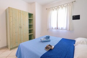 Une chambre à coucher avec un lit, une armoire et une fenêtre avec des rideaux.