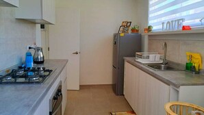Une cuisine de taille réduite équipée d’une cuisinière à gaz, d’un réfrigérateur et d’un évier.