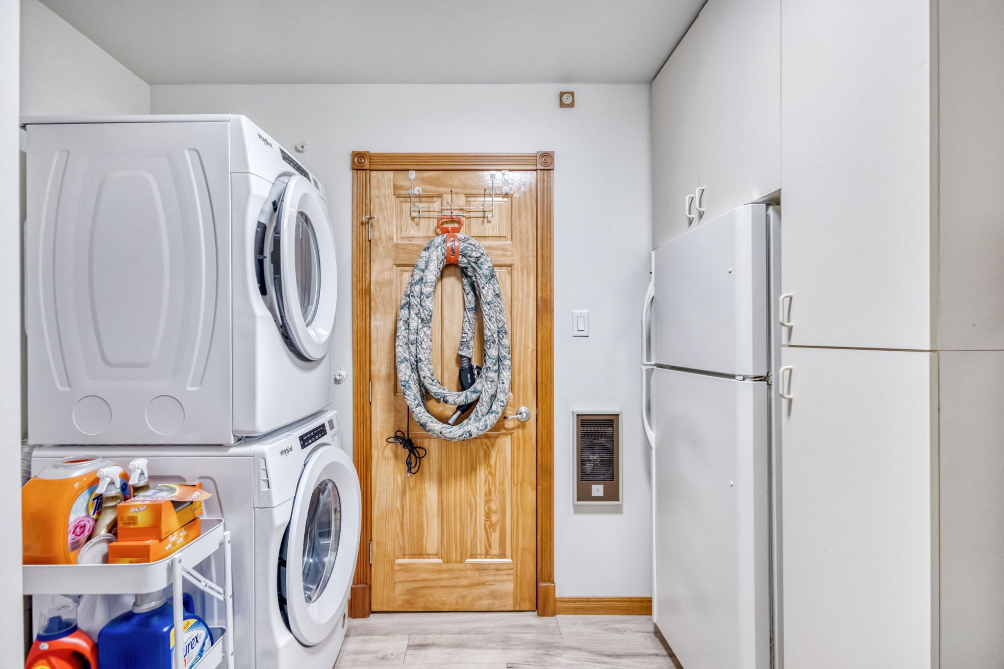 Un lavadero con lavadora, secadora y una puerta de madera decorada con un adorno.