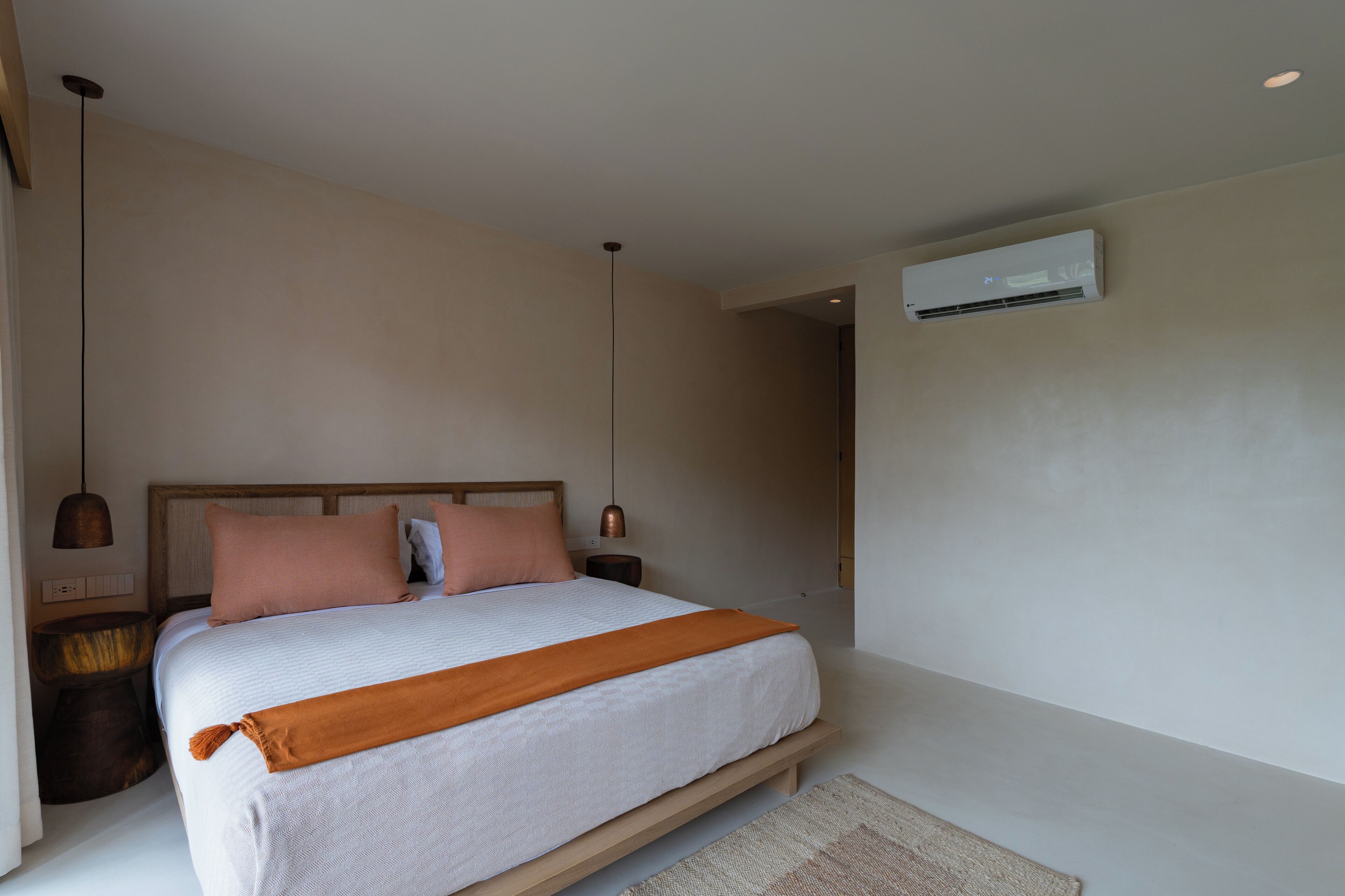Un dormitorio con cama, mesitas de noche, un equipo de aire acondicionado y un aplique de pared.