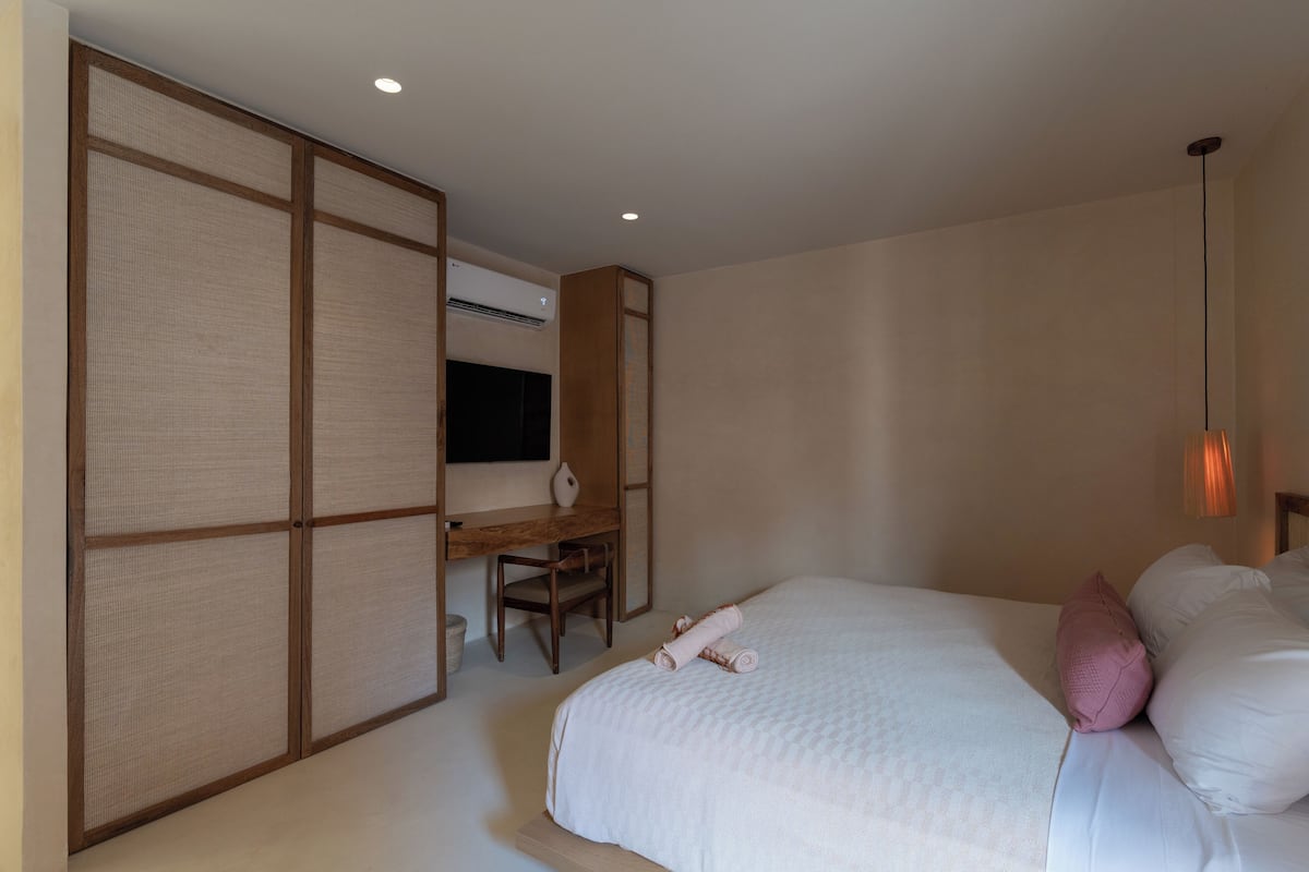 Quarto de hotel com uma cama, escrivaninha e televisão.