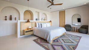 A modern bedroom with a bed, bedside tables, a ceiling fan, and a patterned rug. - Aflora Tulum  (Tulum)
