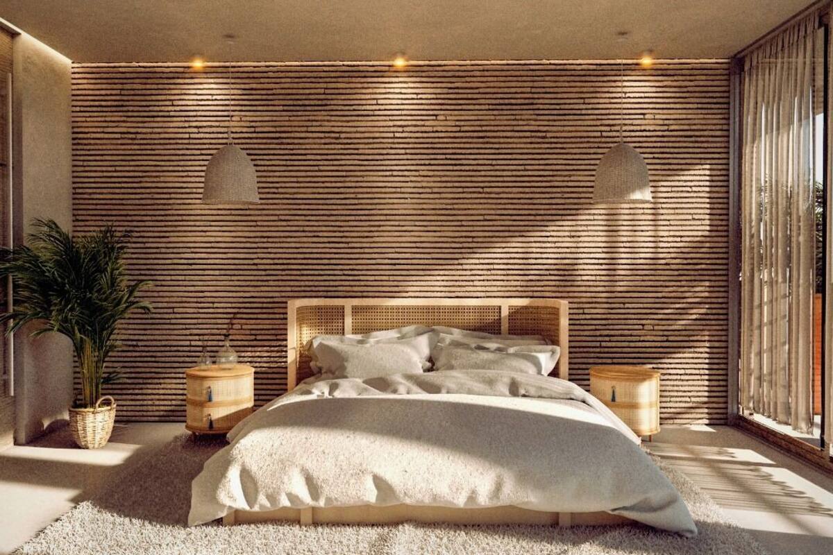 Quarto moderno com painel ripado de madeira, uma cama grande, duas mesas de cabeceira e um vaso com planta.