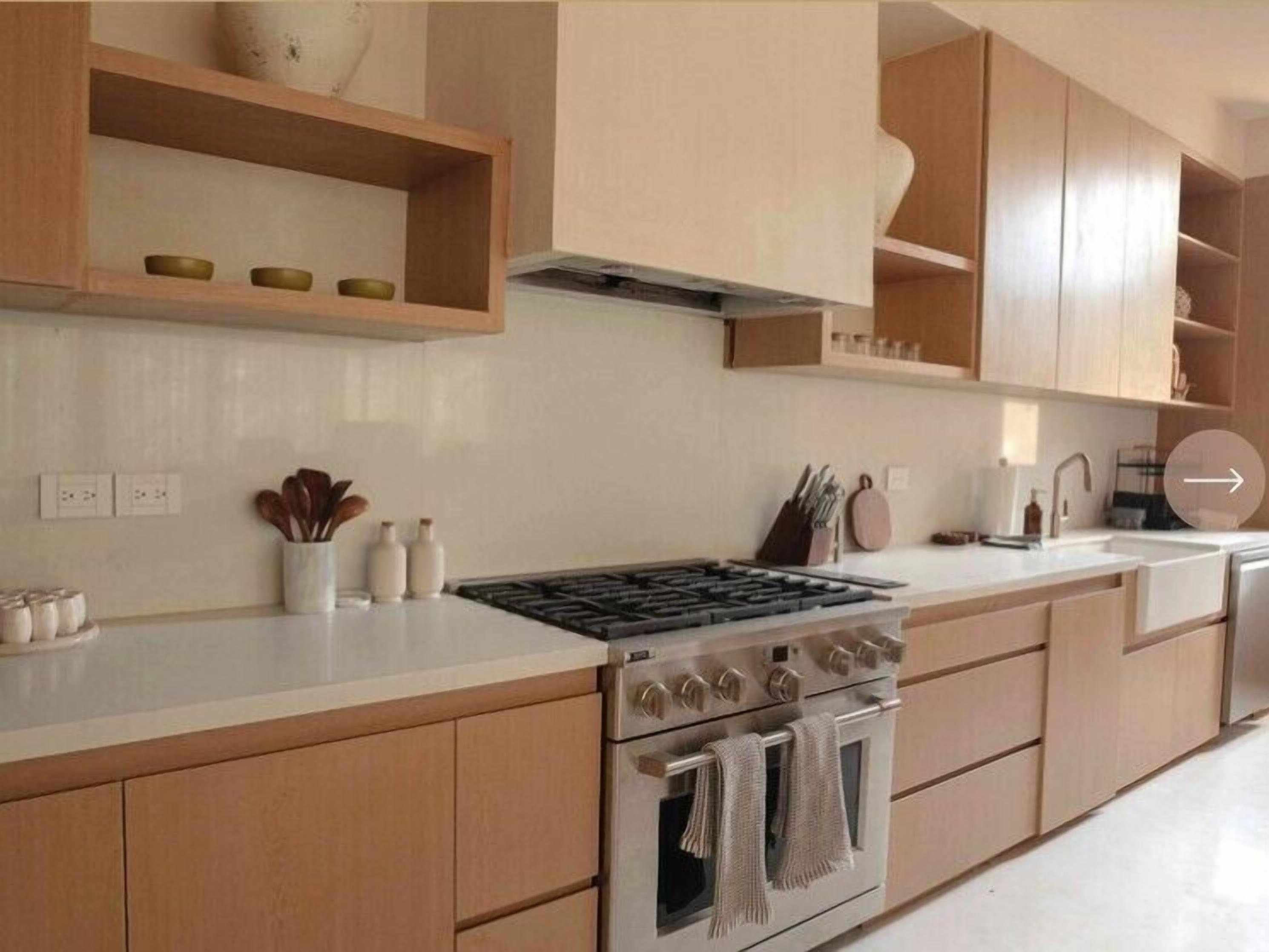 A modern kitchen with wooden cabinets, a stainless steel stove, and a white countertop.
