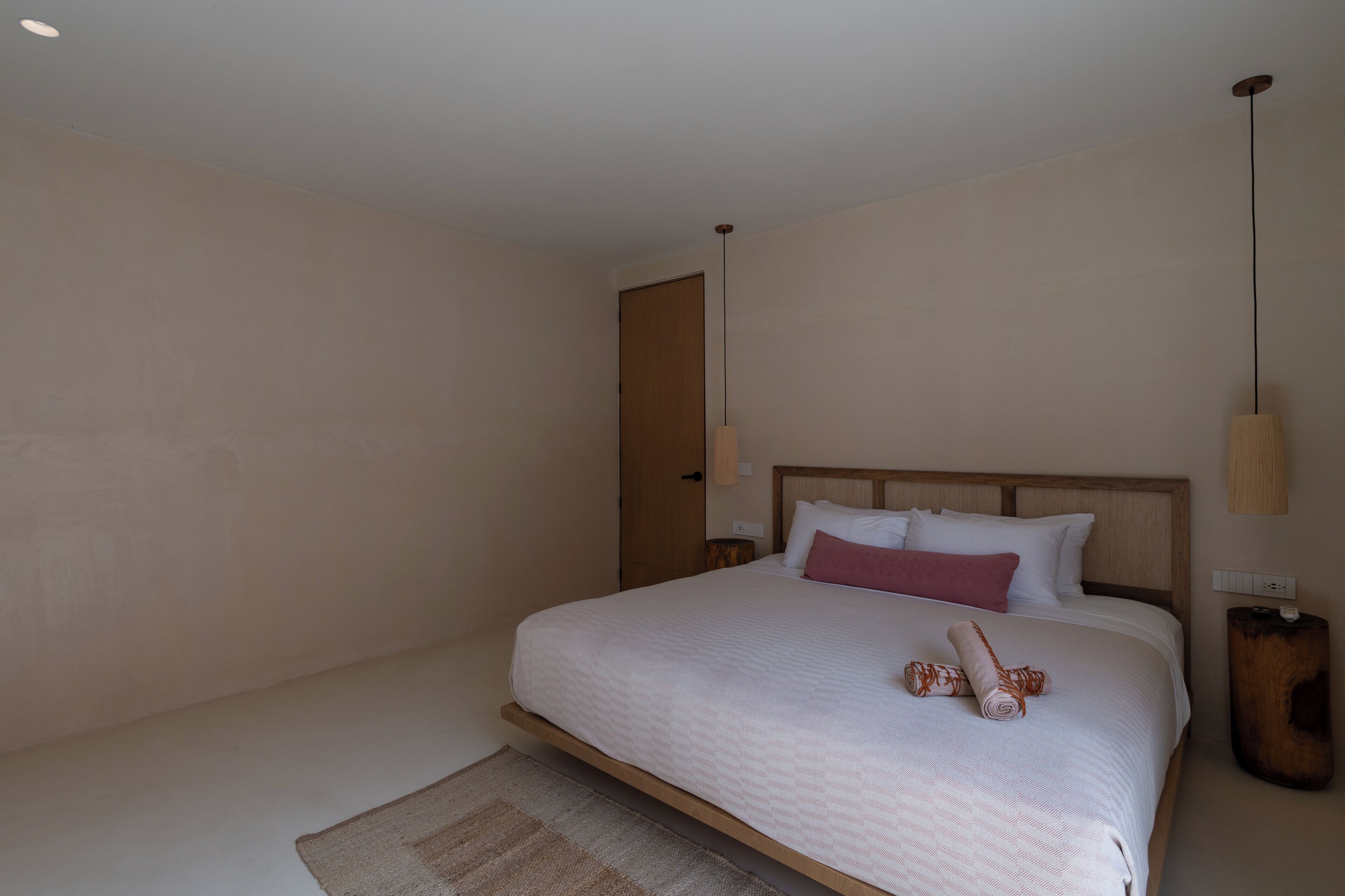 A spacious bedroom with a large bed, wooden headboard, and a wooden nightstand.