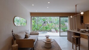 A modern living room with a sofa, coffee table, and a view of a garden through large sliding doors. - Aflora Tulum  (Tulum)