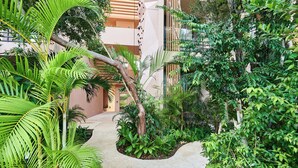 A pathway flanked by lush greenery and a building with a geometric facade. - Aflora Tulum  (Tulum)