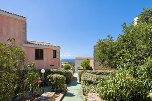 A narrow pathway flanked by buildings with a view of the sea.