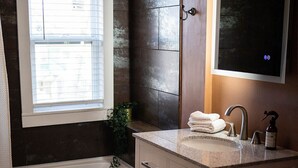 A bathroom with a bathtub, a sink with a mirror, and a toilet.