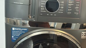 A front view of a GE Profile washer with a front-loading door, control panel, and a label indicating it is a 'Smarter Laundry' model. - Peaceful Marshside Escape -Family Friendly- Easy Beach Access • Outdoor Living (Hilton Head Island)