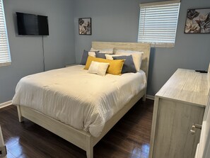 A bedroom with a bed, a TV mounted on the wall, and artwork on the walls.