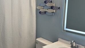 A bathroom with a toilet, sink, and shower curtain. - Peaceful Marshside Escape -Family Friendly- Easy Beach Access • Outdoor Living (Hilton Head Island)