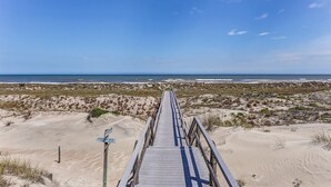Una pasarela de madera que conduce a una playa con cielo despejado.
