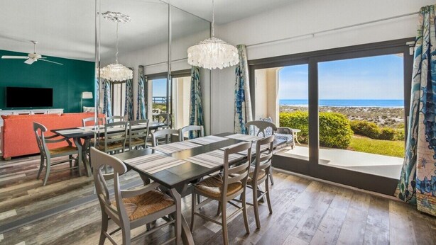 Un comedor moderno con una mesa grande y sillas, un televisor y vistas al océano.