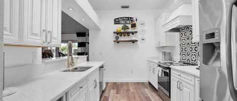 Una cocina moderna con armarios blancos, una isla central y un refrigerador de acero inoxidable.