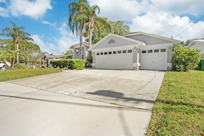 A residential house with a garage, a driveway, and a well-maintained lawn. - Designer's Gorgeous Lake House with King Bed on Lake Tarpon (Palm Harbor)