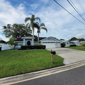 A residential house with a garage, a well-maintained lawn, and a mailbox. - Designer's Gorgeous Lake House with King Bed on Lake Tarpon (Palm Harbor)