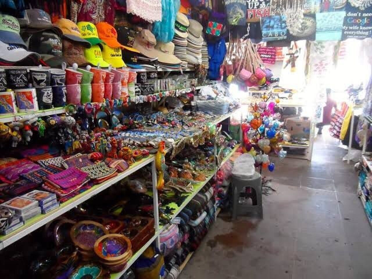 A market stall with various items on display including hats, toys, and other souvenirs.