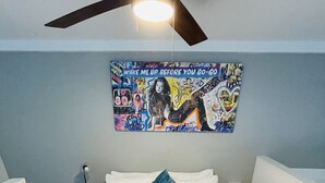 A room with a bed, a ceiling fan, a wall with a colorful poster, and a small table. - NEW Cozy Downtown East Austin Condo - Prime Location! 10 min walk to Rainey St (Austin)