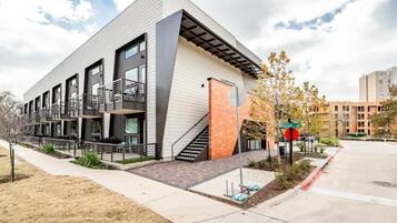 A modern building with a flat roof, large windows, and a staircase leading to an upper level.