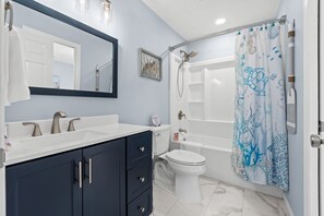 Une salle de bain avec deux lavabos, des toilettes, une baignoire et une douche.