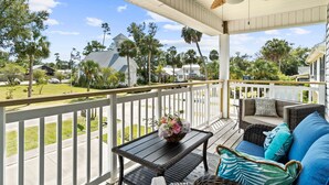 A covered porch with wicker furniture, a table with a flower arrangement, and a view of a church and residential homes. - Short  Walk to beautiful St Joe Bay and Historic downtown Port St Joe.  (Port St. Joe)