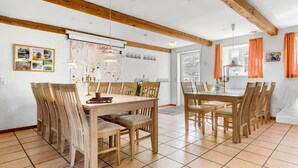 A dining area with wooden tables and chairs, a whiteboard with children's drawings, and a window with orange curtains. - 7 bedroom awesome home in Rønde (Rønde)