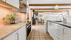 A modern kitchen with white cabinetry, a central island, and a hanging pendant light. - 7 bedroom awesome home in Rønde (Rønde)