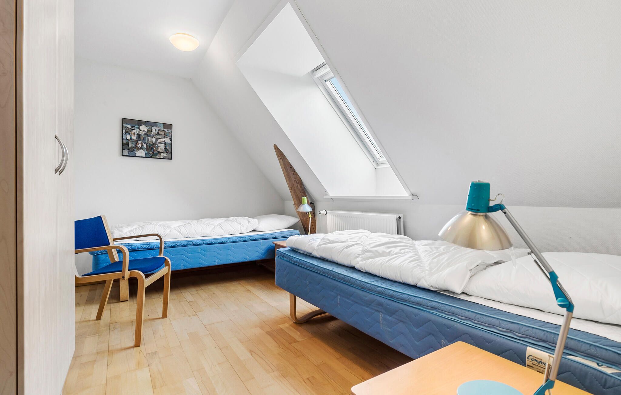 Una camera del dormitorio con due letti, una scrivania, una sedia e un lucernario.