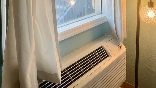 Une pièce avec une fenêtre, un radiateur et un luminaire fixé au mur.