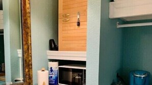 Une salle de bain équipée d’un lavabo, d’un miroir, d’un porte-serviettes et d’un réfrigérateur Galanz bleu.