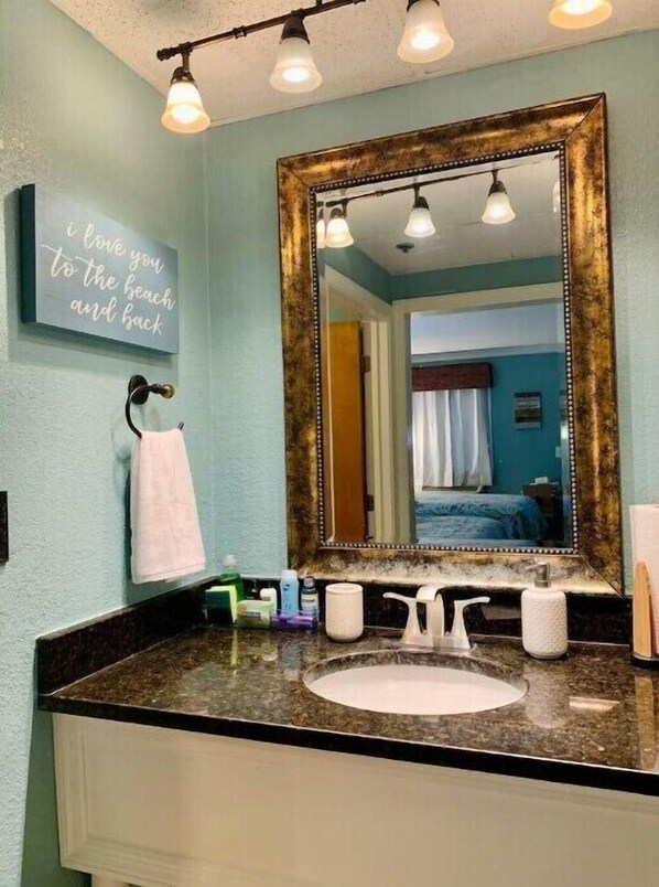 A bathroom with a large mirror, a sink, and a towel rack. A sign on the wall reads "I love you to the beach and back." - Perfect Location at Tybee Island!
(Tybee Island)