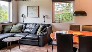A modern living room with a leather sofa, a small round table, and a dining table with chairs. There are two wall-mounted lamps and a framed map on the wall. - Awesome home in Nordborg with kitchen (Nordborg)