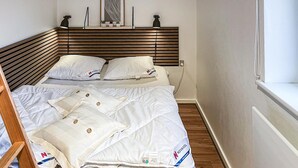 A neatly made bed with white bedding and pillows, a wooden headboard, a framed artwork above the bed, and a bedside lamp. - Awesome home in Nordborg with kitchen (Nordborg)