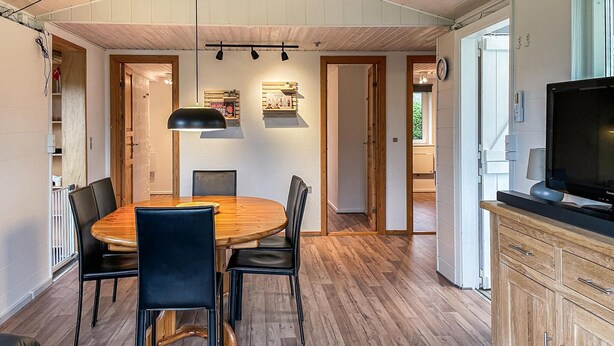 A dining area with a wooden table and chairs, a pendant light, and a television on a cabinet. - Awesome home in Nordborg with kitchen (Nordborg)