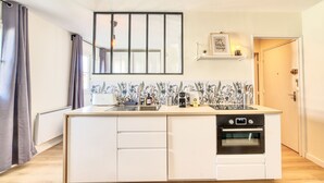 A modern kitchen with a built-in oven, a sink, and a window above the countertop. - Le Verde - Ravissant appartement cosy (Saint-Genis-Laval)