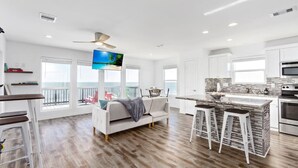 A modern kitchen with a large island, bar stools, and a view to the outside. - Cabn By the Sea Ultra Secluded Beachfront Home (Bolivar Peninsula)