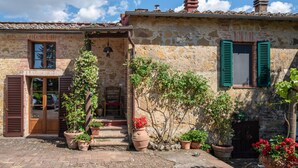 A rustic stone building with a wooden door, green shutters, and potted plants. - Beautiful home in Siena with WiFi (Siena)