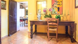 A hallway with a wooden desk, chairs, a vase with flowers, and a painting on the wall. - Beautiful home in Siena with WiFi (Siena)