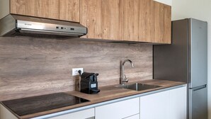 Une cuisine moderne avec des meubles en bois, une hotte de cuisinière en acier inoxydable, un évier et un réfrigérateur encastré.