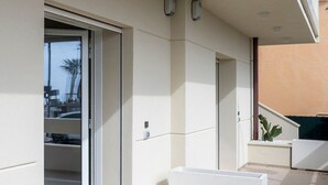 Un bâtiment moderne doté d’une porte-fenêtre coulissante, d’un petit espace extérieur aménagé en coin salon et d’un escalier menant à un étage supérieur.