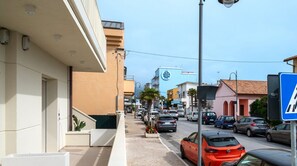 A street view with buildings, parked cars, and a clear sky.