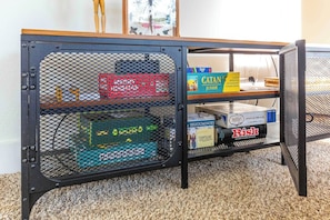 A metal-framed storage unit with shelves holding board games and books. - Wilderness Haven with Hot Tub in Franktown (Franktown)