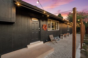 A building with a dark exterior, a front door, a window, and a bench outside. - Wilderness Haven with Hot Tub in Franktown (Franktown)