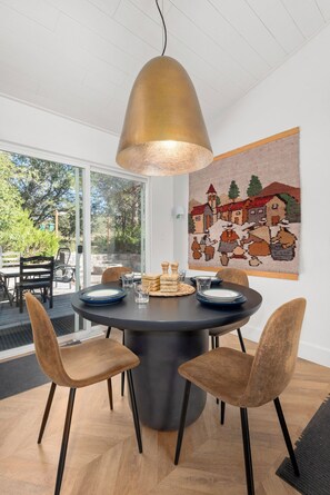 A round dining table with four chairs, a pendant light, and a wall-mounted tapestry. - Wilderness Haven with Hot Tub in Franktown (Franktown)